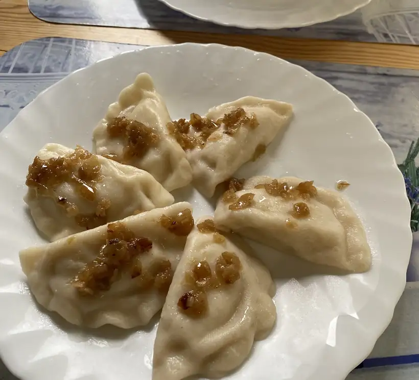 Pierogi polane cebulką na białym talerzu